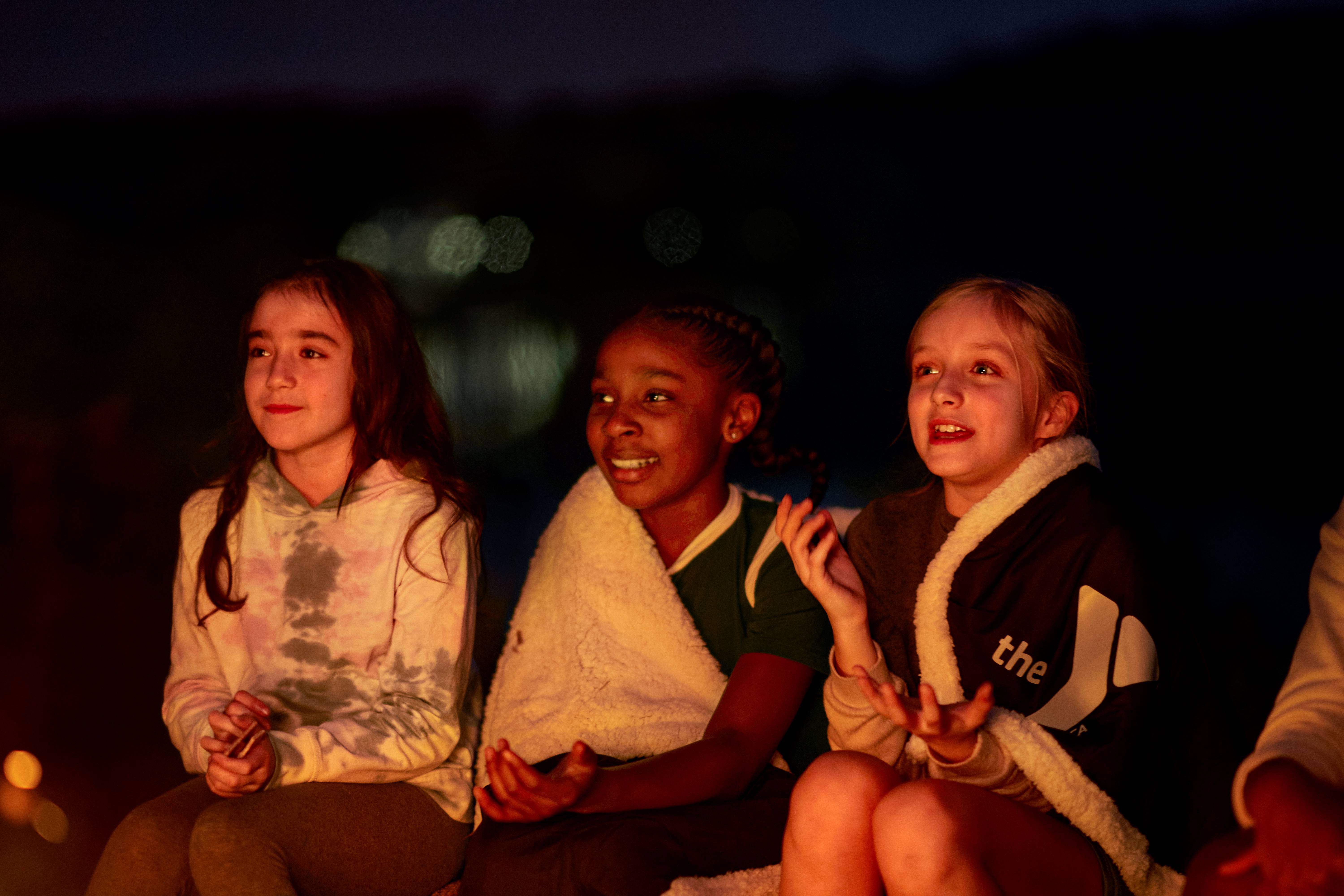 girls sitting around campfire 